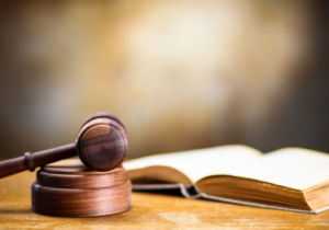 Stock image of an open law book beside a wooden gavel and sound block.